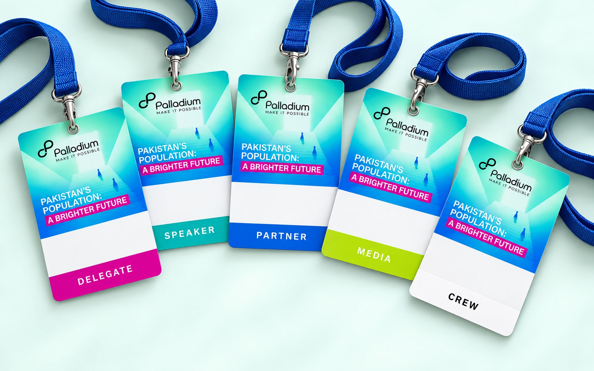 Five name badges on blue lanyards, each with a different coloured band for delegate, speaker, partner, media and crew