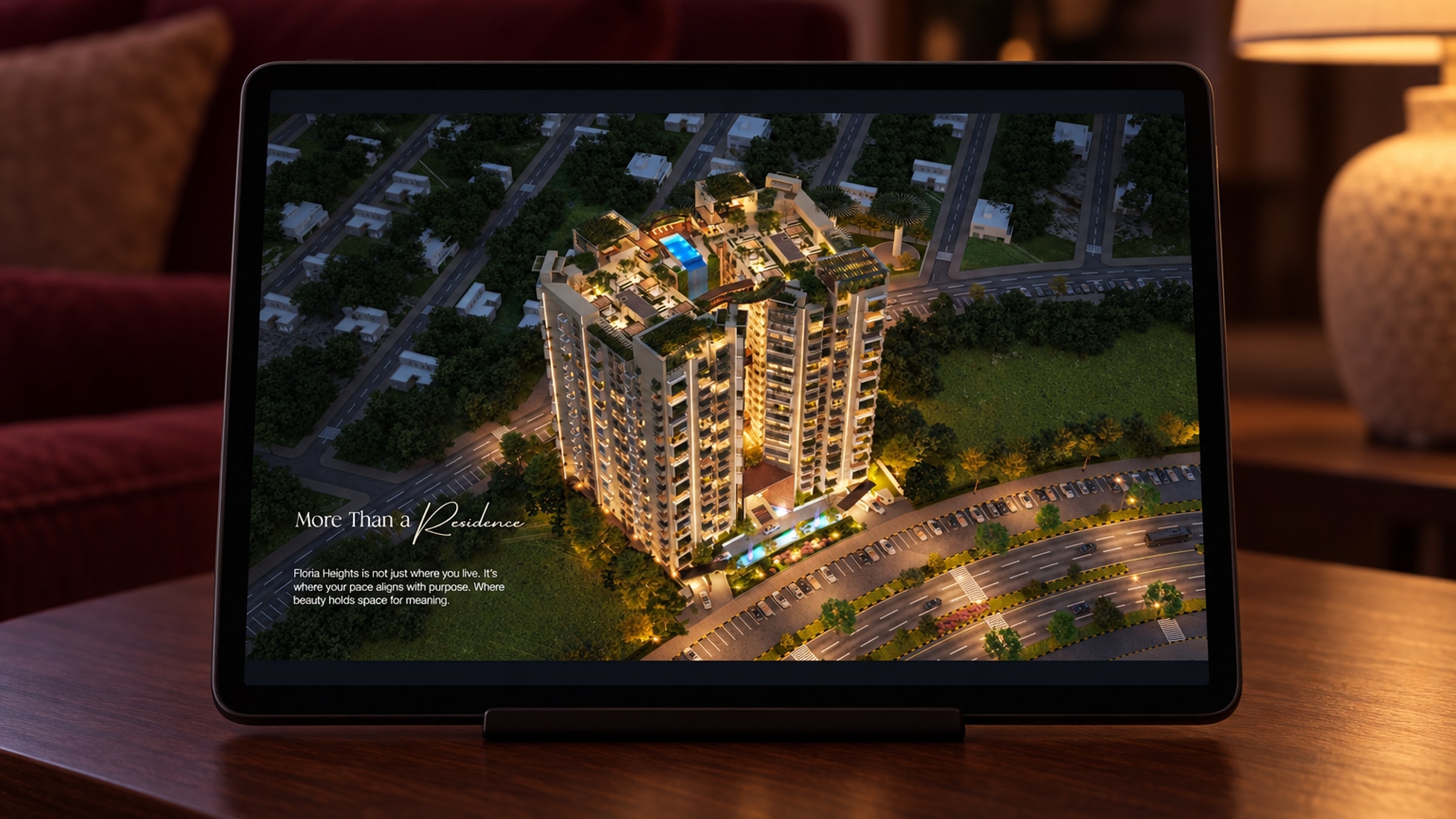 A tablet on a stand on a walnut side table in a dim room, its screen showing the tower at night from above