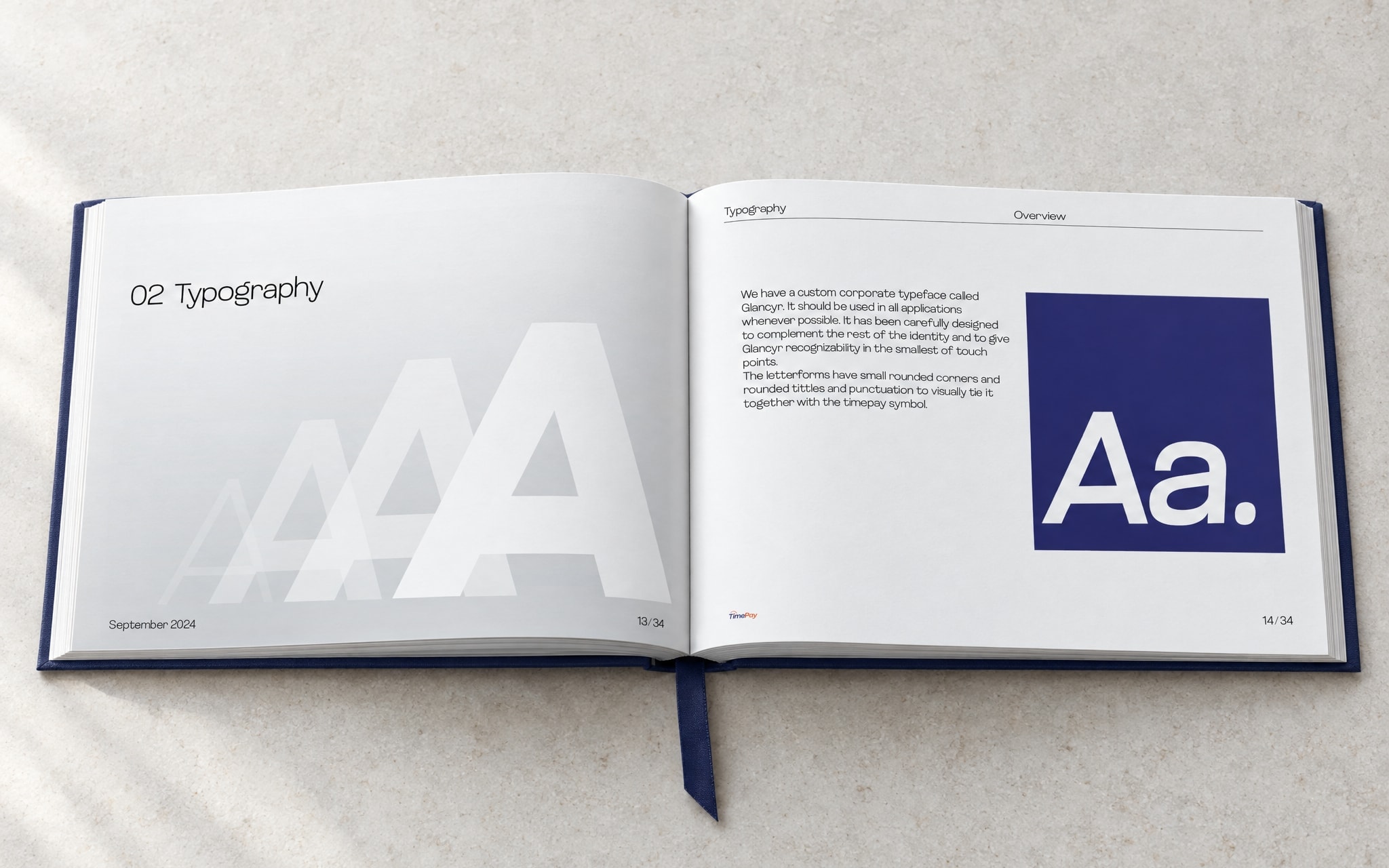 The book open at the typography opener: layered white capitals on the left page, the Glancyr Aa tile on the right