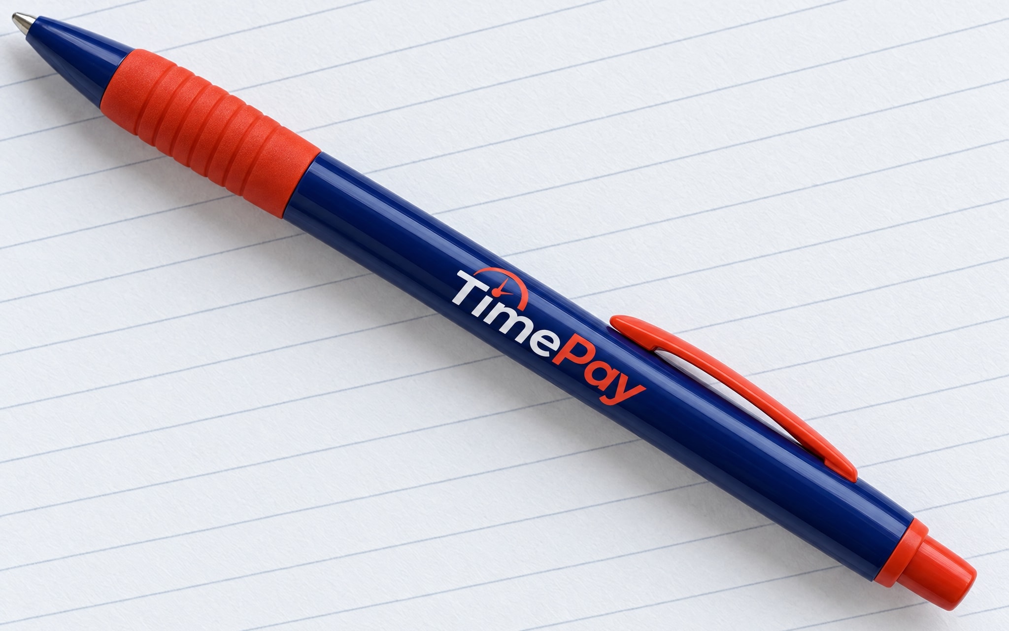 A navy pen with a red-orange grip and the white logotype along the barrel, lying on a ruled page