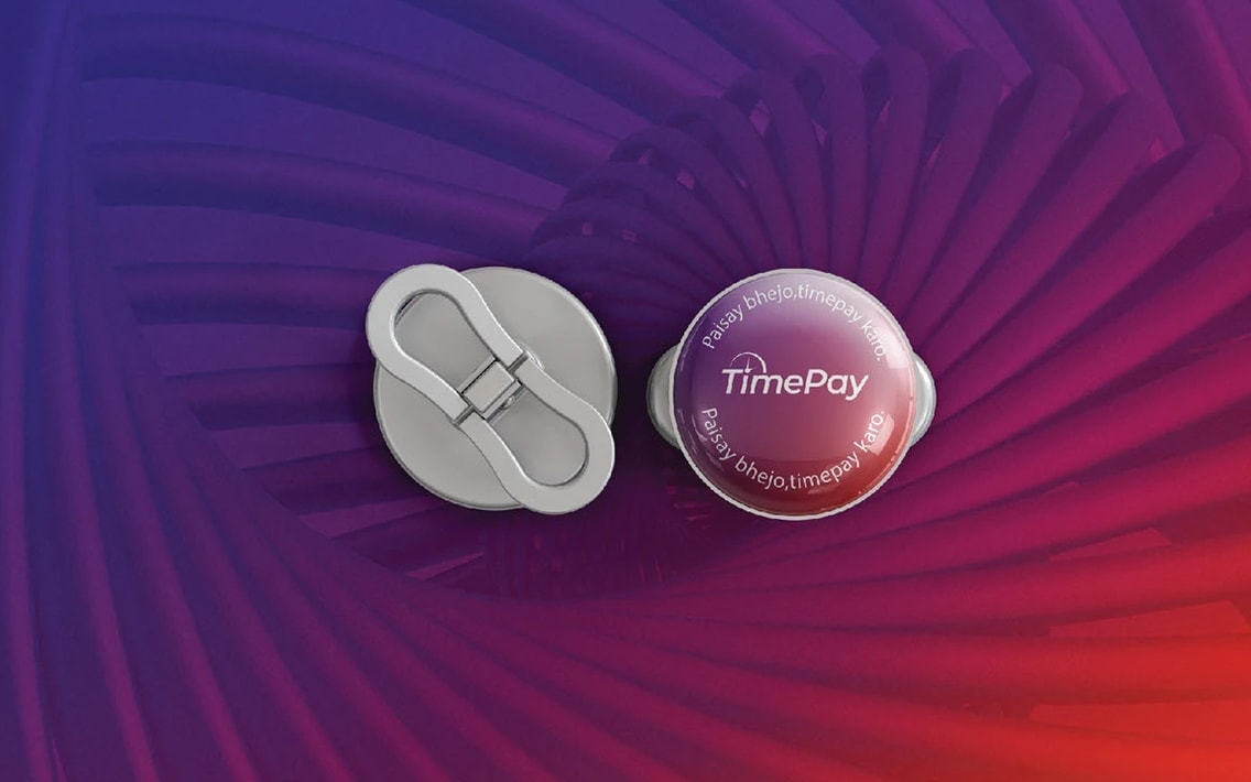 Two enamel pins, one silver and one gradient with the logotype, on a spiral-patterned gradient ground