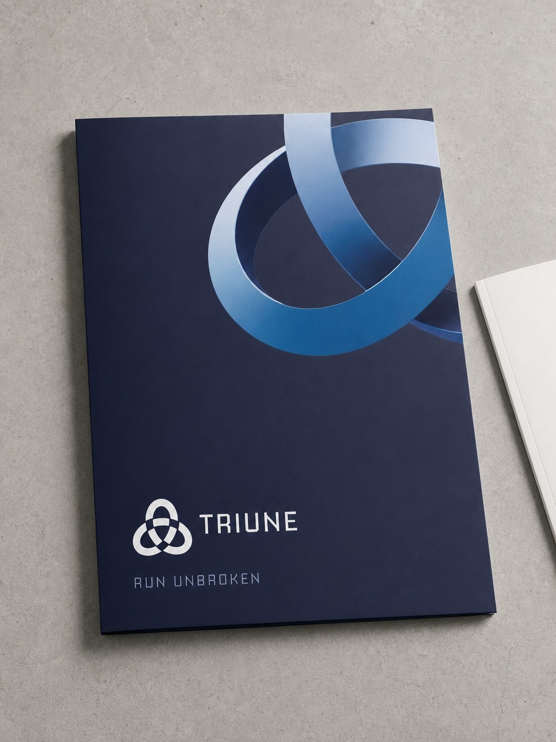A navy matte laminated presentation folder with the mark cropped hard off the top right corner and the lockup and tagline set small at the foot