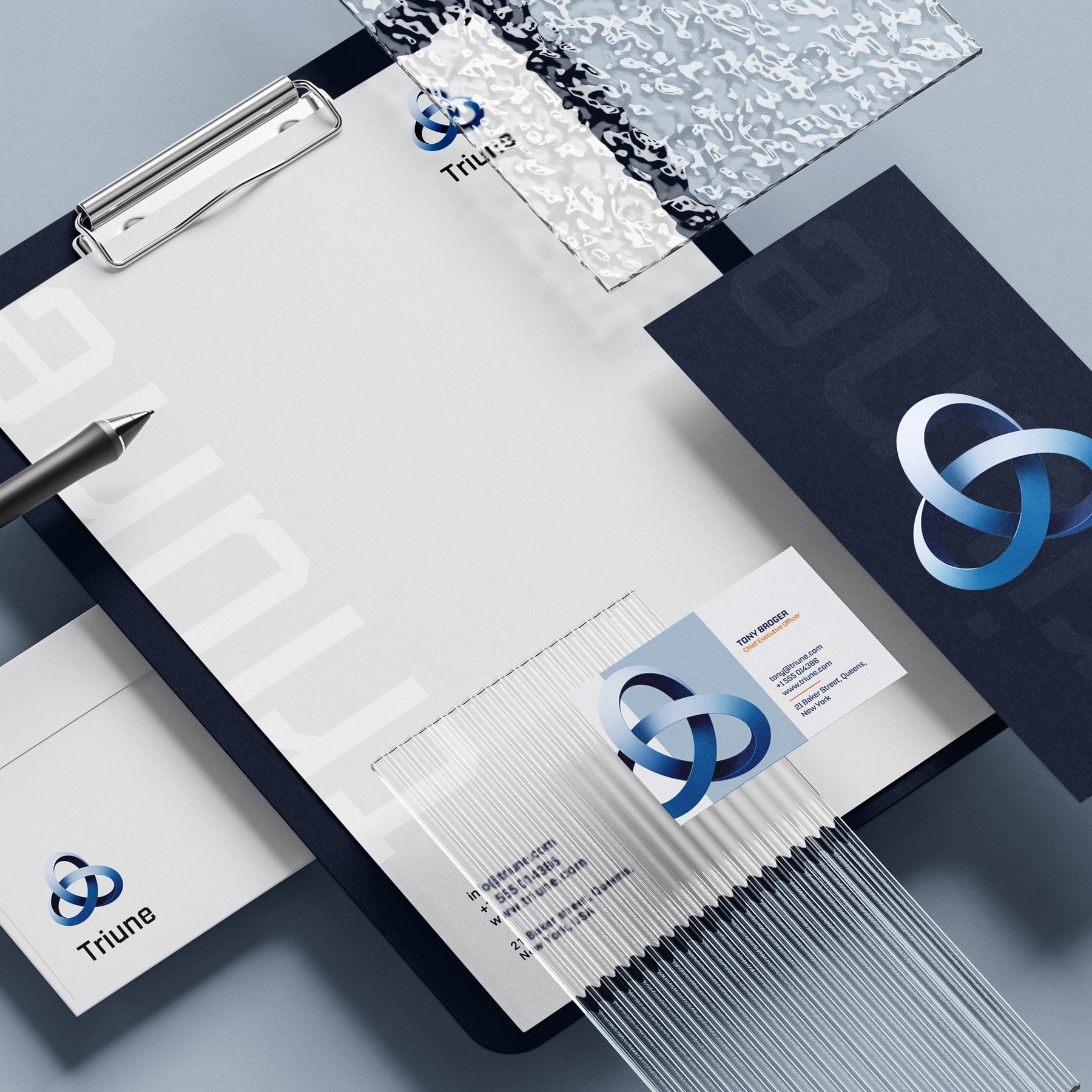 A stationery flatlay: clipboard, letterheads, navy folder and business cards arranged on a pale ground